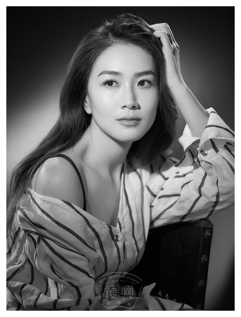 黑白肖像：穿条纹衬衫的女性侧坐在木椅上