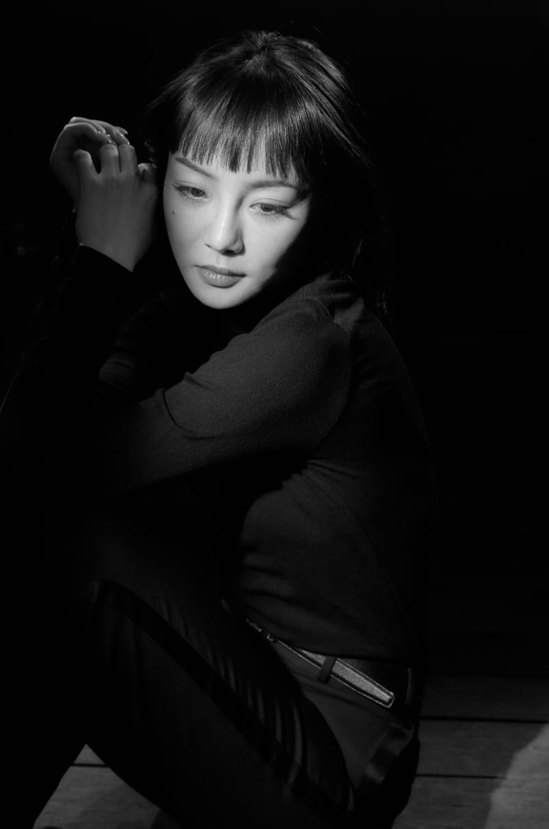 黑白肖像：女性在暗背景中沉默凝视