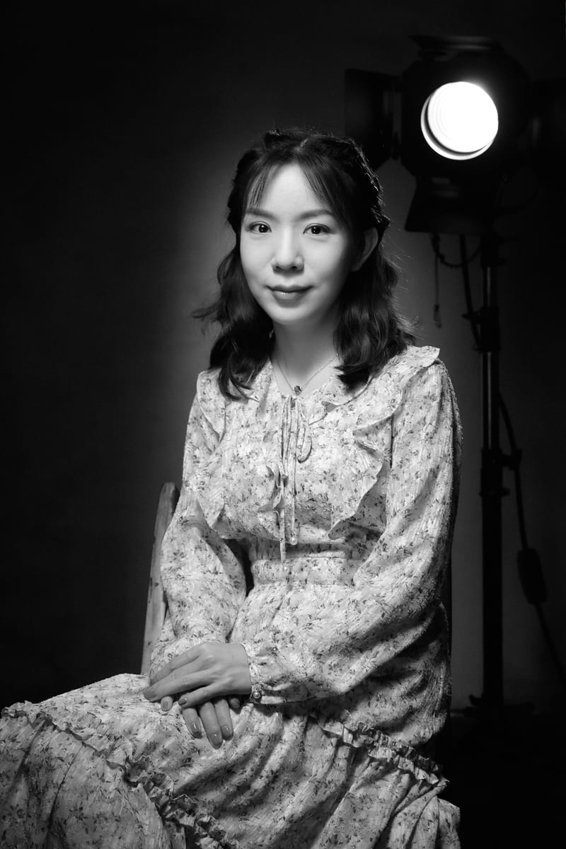 黑白肖像：穿碎花裙的女性坐在灯旁
